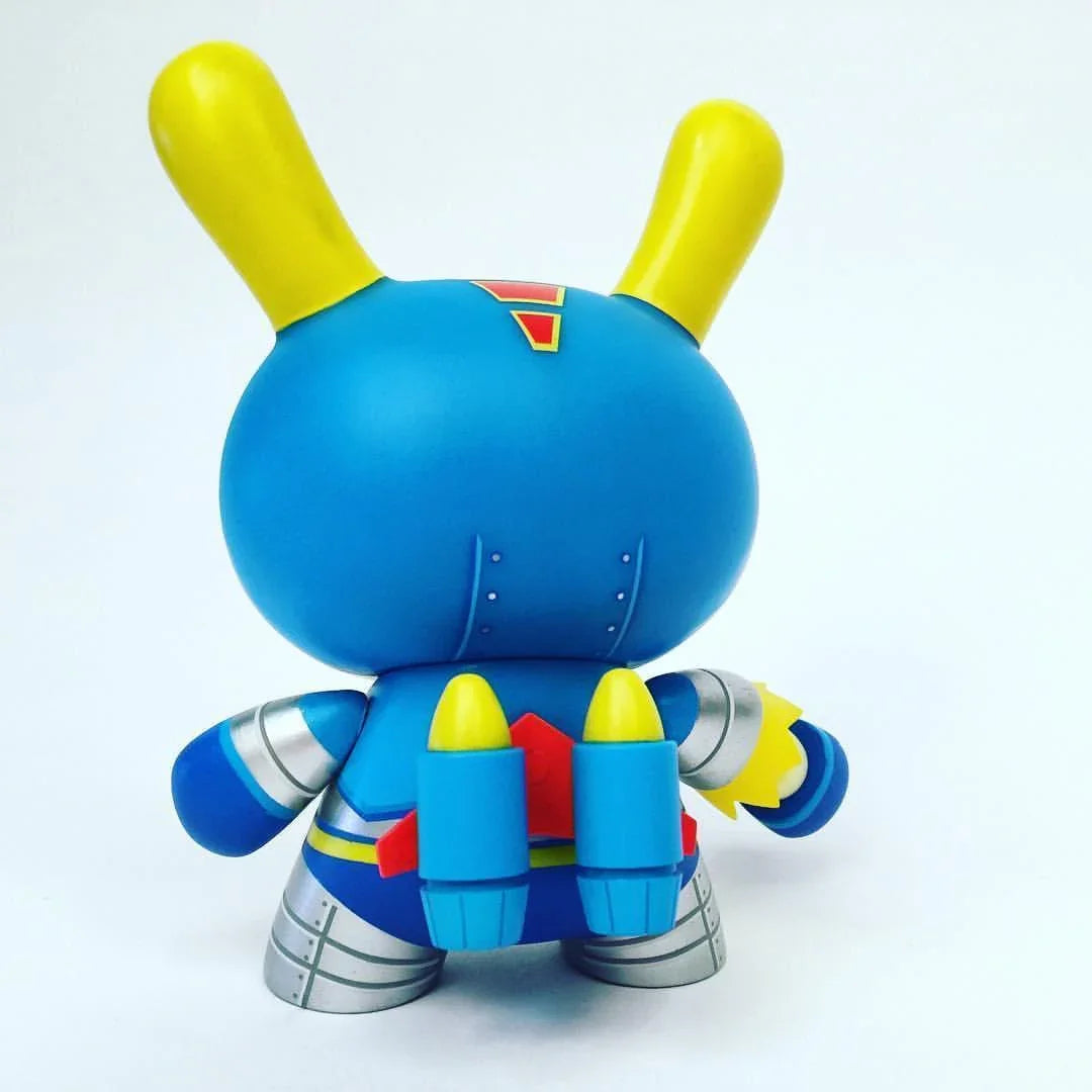 Rear view of Kidrobot designer vinyl toy in blue and yellow superhero costume with jetpack on white background